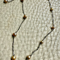 french antique platinum Necklace with pearl beads on a textured beige surface