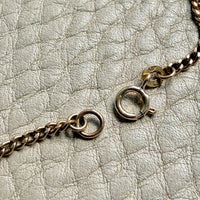 Gold chain necklace on a textured light gray surface