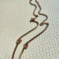 Gold chain necklace on a textured light gray surface