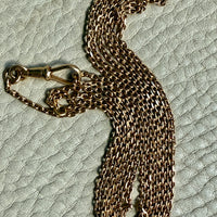 Gold chain necklace on a textured light gray surface. Penelope Penelope vintage 18k gold fine jewelry