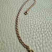 Gold chain bracelet on a textured light green surface
