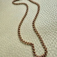 18k vintage yellow gold chain necklace on a textured light green surface