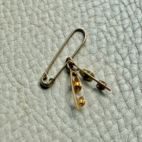 Gold ice skates charm on a textured light gray surface