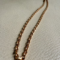 Gold chain necklace on a light gray textured surface