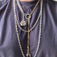 Necklace with multiple chains and pendants on a person wearing a dark blue shirt.