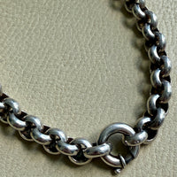 Silver chain bracelet on a textured beige surface