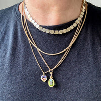 Person wearing multiple necklaces with pendants on a black shirt.