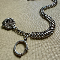 antique Silver watch chain with large bolt clasp on a textured beige surface