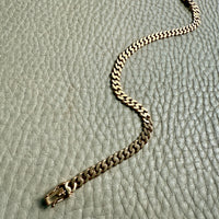 Gold chain bracelet on a textured light gray surface
