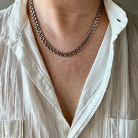 Person wearing a white shirt with a chain necklace