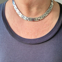 Person wearing a silver chain necklace with a plain background