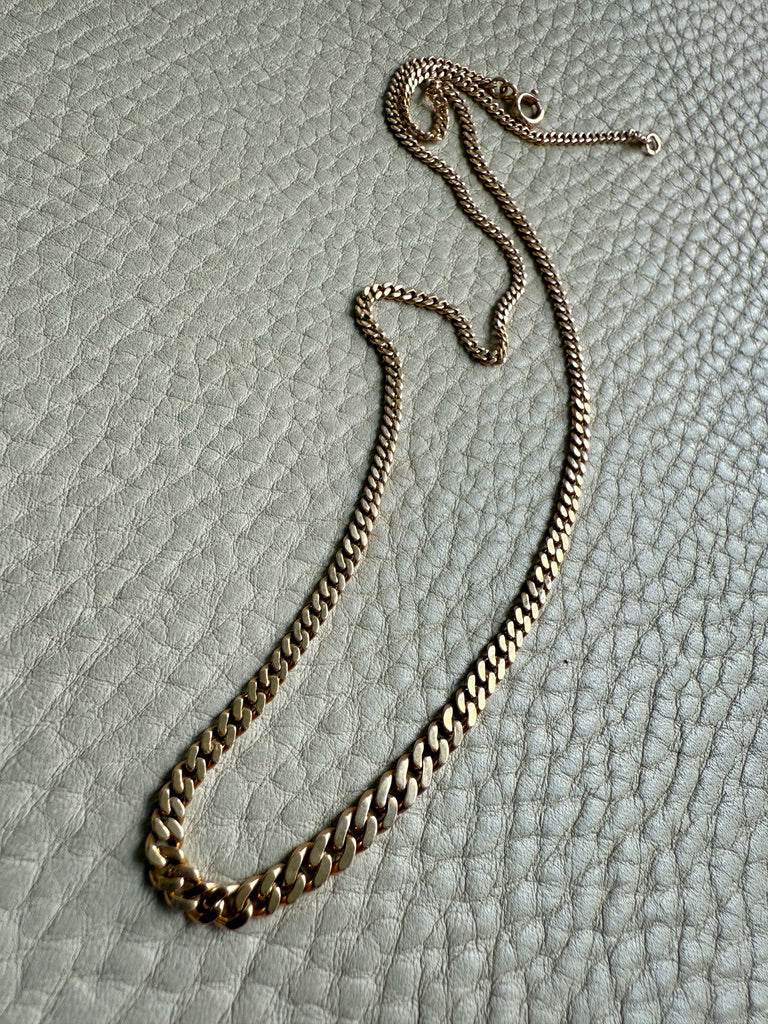 Gold chain necklace on a textured gray surface
