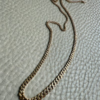 Gold chain necklace on a textured gray surface