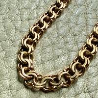 Gold chain necklace on a textured light green surface