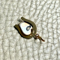 Gold pendant on a textured beige surface