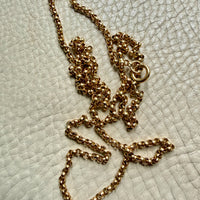 18k Gold antique rolo link necklace on a textured light gray surface