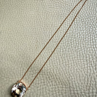 Necklace with a pendant on a textured beige surface