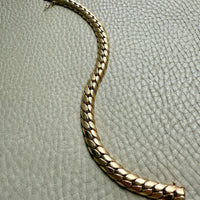 Gold bracelet on a textured light gray surface. Penelope Penelope Vintage 18k gold fine jewelry