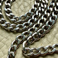 Close-up of a vintage 14k white gold chain on a textured beige surface