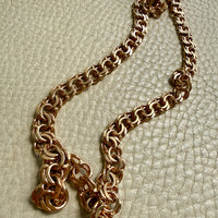 18k gold vintage link necklace on a cream leather surface