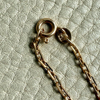 Gold chain necklace on a textured light gray background