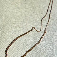 18k gold antique chain necklace on a textured light gray background