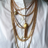 Multiple gold necklaces on a white shirt
