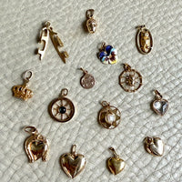Collection of various small gold charms on a textured light gray surface