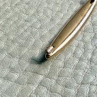 Gold brooch on a textured light gray surface