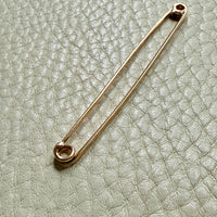 18k Gold antique safety pin brooch on a textured light gray background PenelopePenelope.com