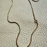 Vintage Italian 18k Gold wheat link necklace on a textured gray surface PenelopePenelope.com