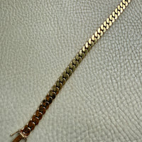 Gold chain bracelet on a textured gray surface