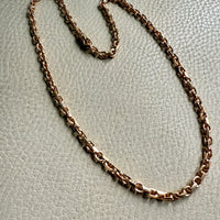 18k gold chain necklace on a light gray textured surface