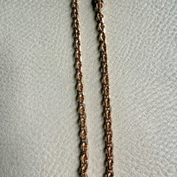 Gold chain necklace on a textured light gray background