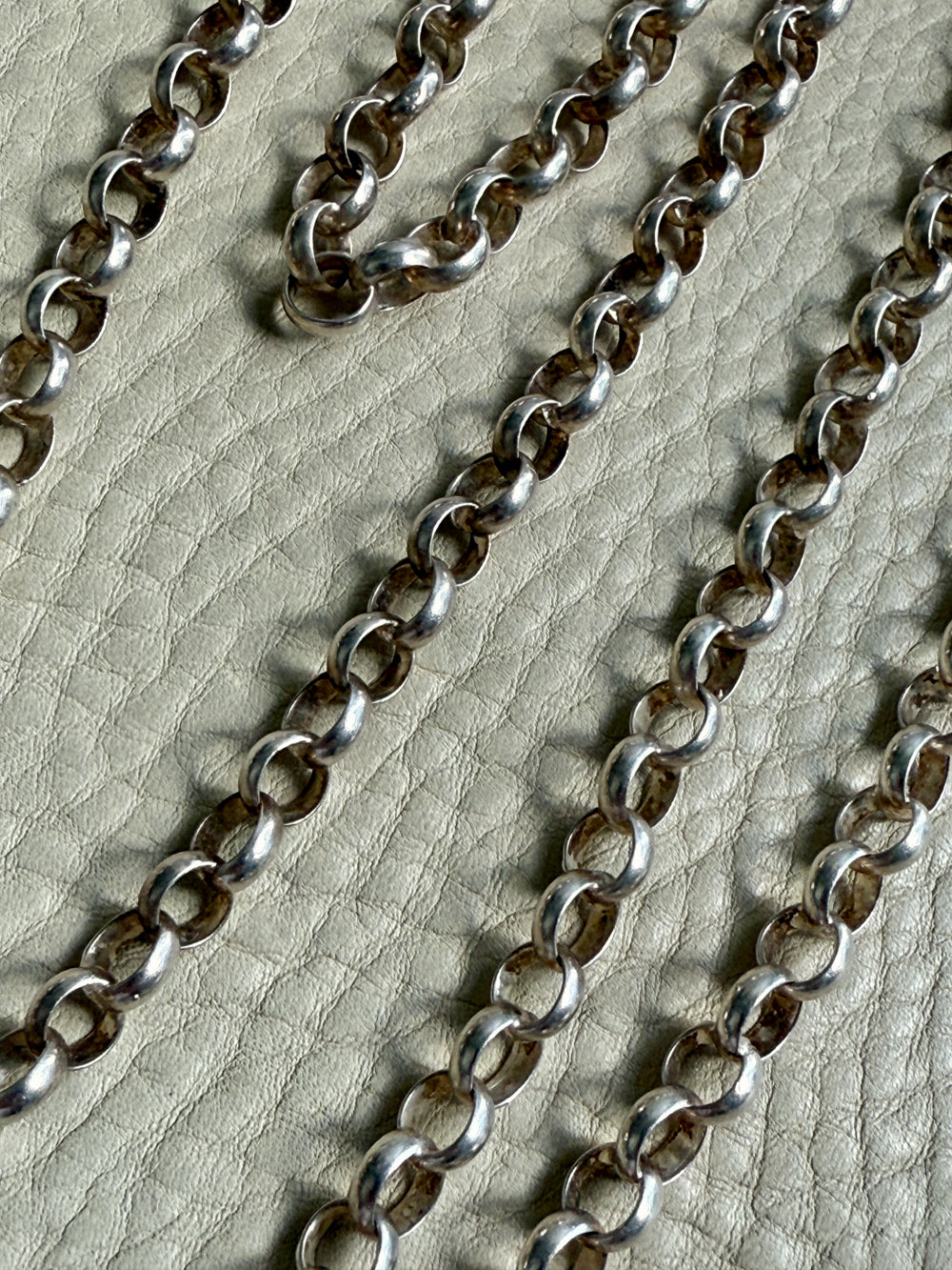Silver chain on a textured beige surface