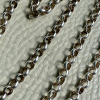 Silver chain on a textured beige surface