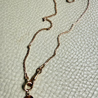 Necklace with a shell pendant on a textured light green surface