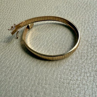 Gold bracelet on a textured light gray surface