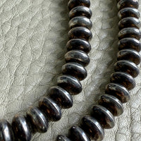 Close-up of a string of silver Navajo pearls on a textured gray background