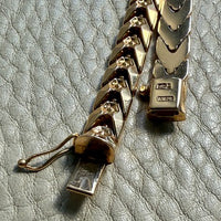 Gold chain bracelet on a textured gray surface