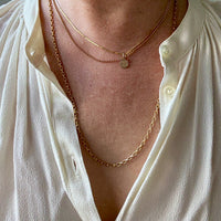 Close-up of a person wearing a white shirt with gold necklaces.