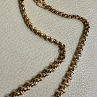 18k Gold rolo chain vintage necklace on a textured light gray background penelopepenelope.com