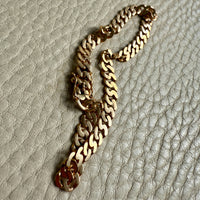 18k Gold chain bracelet on a textured beige surface