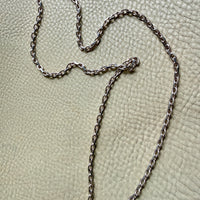 Silver chain necklace on a textured beige surface