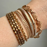 vintage 18k Gold bracelets on a wrist with a neutral background