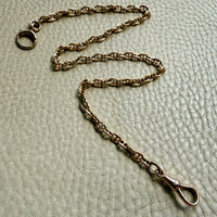 Gold chain necklace on a textured beige background