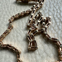 Gold chain necklace on a textured beige surface