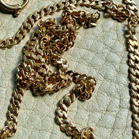 18k gold watch chain necklace on a textured light gray background