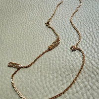 18k Gold chain necklace on a textured light green surface penelopepenelope.com