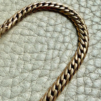 18k vintage Gold curb chain bracelet on a textured light gray surface